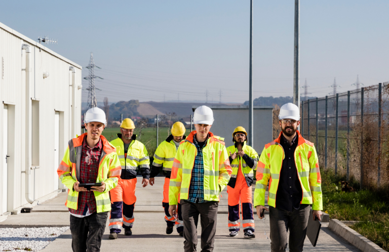 Grupo de inspectores de seguridad Grupo de trabajadores inspectores de seguridad con chalecos reflectantes y cascos, caminando en un entorno industrial.